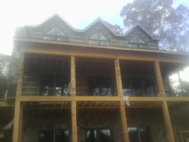 Dormers and porch framing on a large log home under construction — Roof Coating work by our crew in North Lima