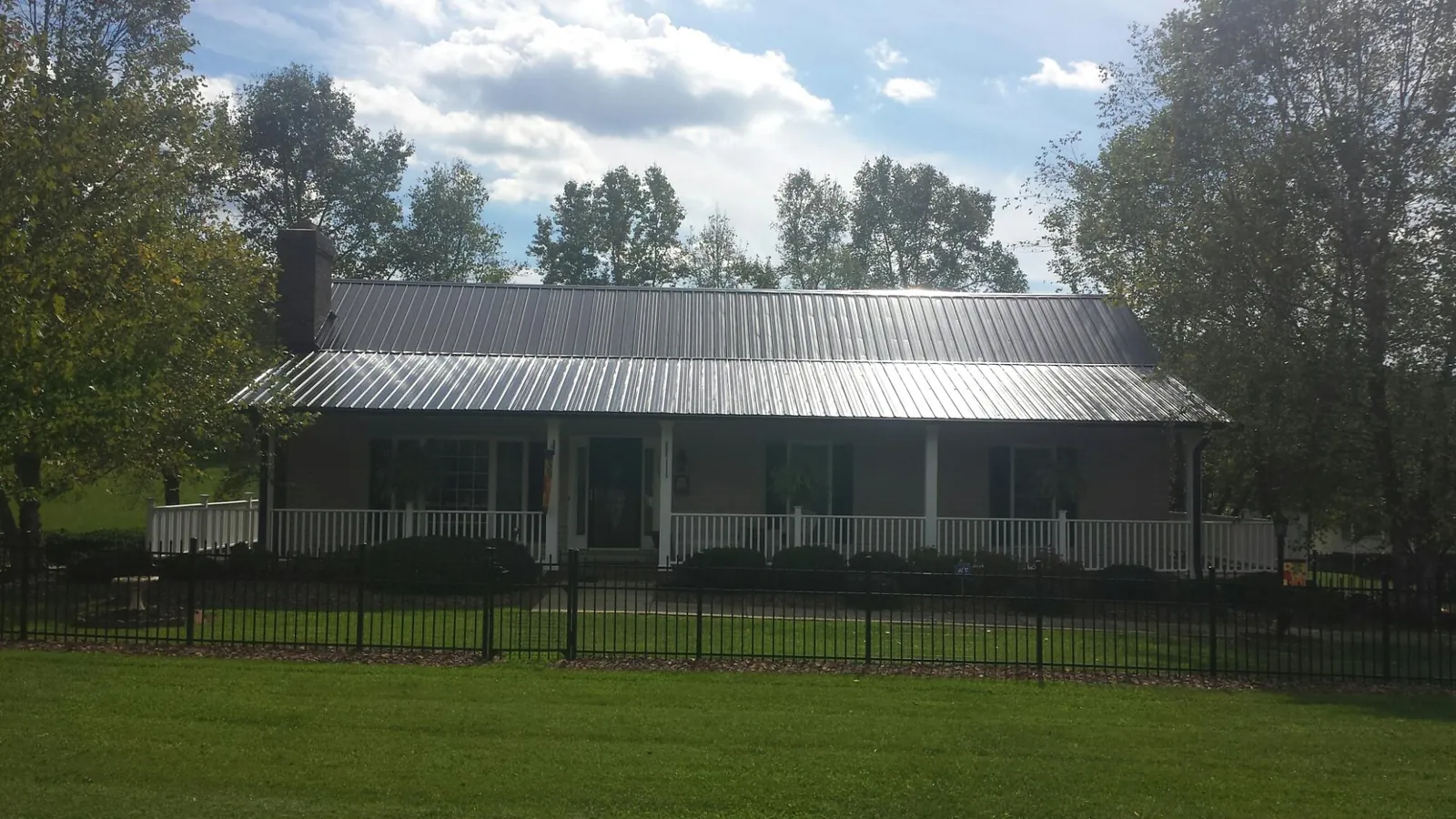 Gray metal roof on a brick ranch with a full width front porch — Gutter Guard Installation work by our crew in North Lima