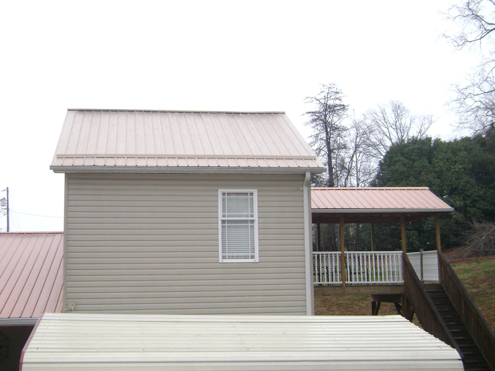 Tan metal roofs on a two story addition and attached porch, from a Roof Replacement job in North Lima